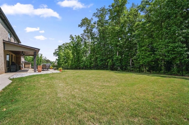 view of yard featuring a patio, a ceiling fan, and fence
