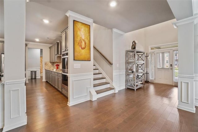 foyer featuring a decorative wall, a wainscoted wall, recessed lighting, ornate columns, and dark wood-style floors