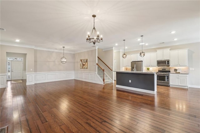 kitchen with pendant lighting, white cabinetry, a kitchen island with sink, stainless steel appliances, and dark hardwood / wood-style flooring