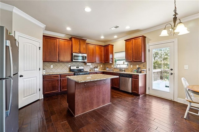 kitchen with tasteful backsplash, appliances with stainless steel finishes, dark wood-type flooring, a sink, and a kitchen island