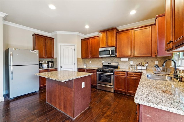 kitchen with appliances with stainless steel finishes, a sink, dark wood finished floors, and crown molding