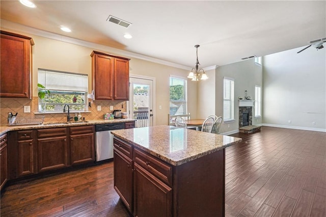 kitchen featuring visible vents, dishwasher, dark wood-style floors, a stone fireplace, and a sink