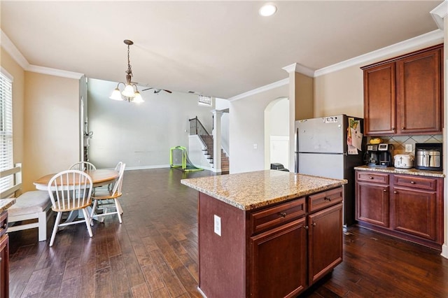 kitchen with crown molding, arched walkways, decorative backsplash, and dark wood-type flooring