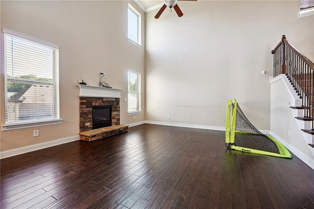 unfurnished living room with stairway, baseboards, wood finished floors, and a stone fireplace