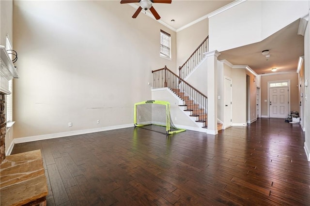 unfurnished living room with ornamental molding, stairway, wood finished floors, and a towering ceiling