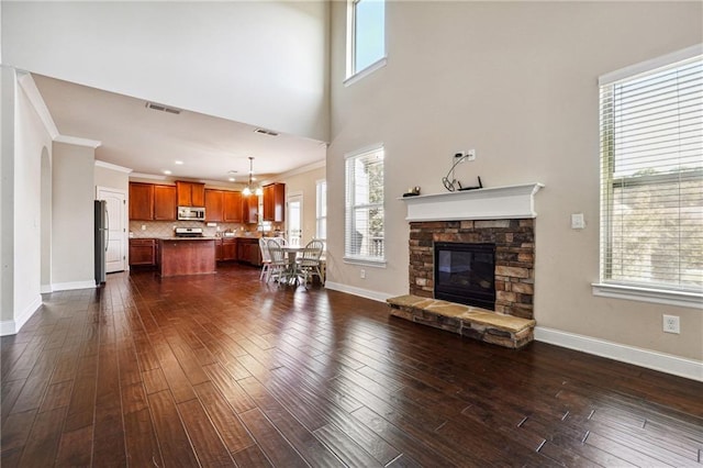 unfurnished living room with visible vents, dark wood finished floors, a wealth of natural light, and ornamental molding