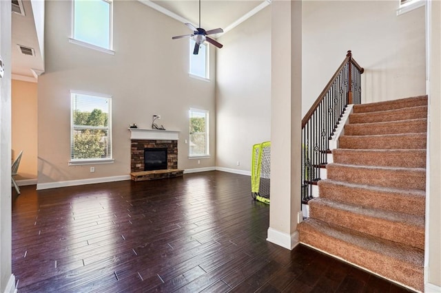 unfurnished living room featuring plenty of natural light, visible vents, dark wood finished floors, and a stone fireplace