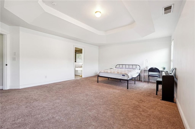 bedroom with carpet floors, a tray ceiling, visible vents, ensuite bath, and baseboards