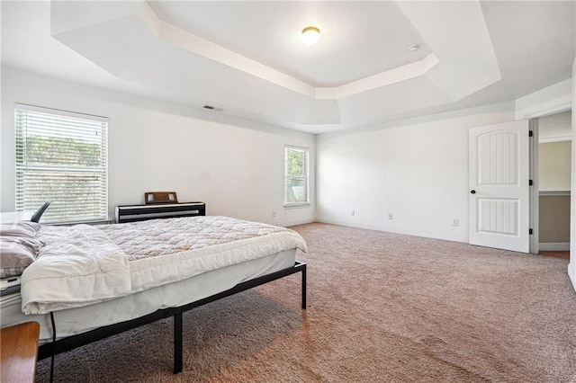 bedroom with a raised ceiling, carpet flooring, visible vents, and baseboards