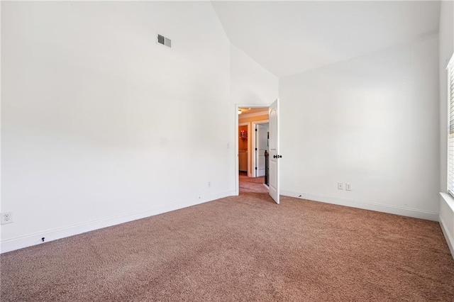 empty room featuring light carpet, high vaulted ceiling, visible vents, and baseboards