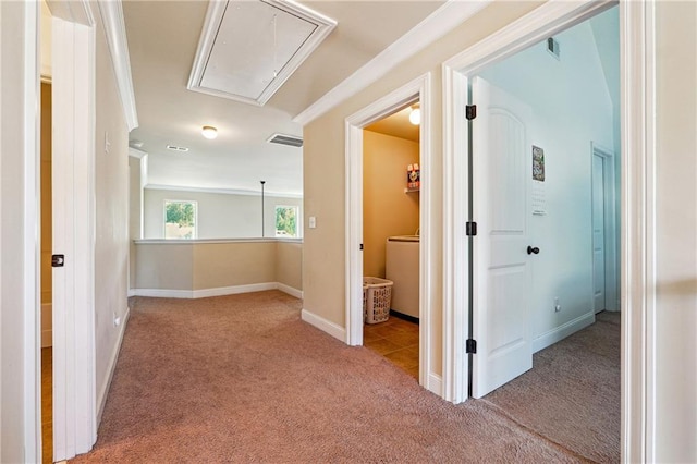 hall featuring attic access, visible vents, ornamental molding, and carpet floors