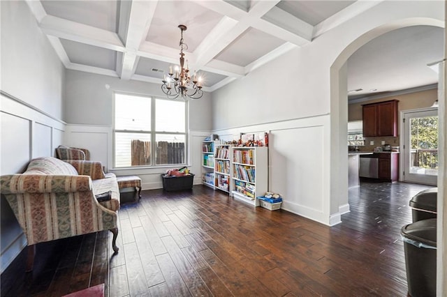 living area with coffered ceiling, arched walkways, dark wood-style flooring, and beamed ceiling