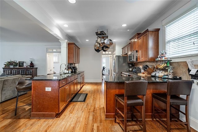 kitchen featuring kitchen peninsula, a kitchen breakfast bar, light wood-type flooring, ornamental molding, and stainless steel appliances