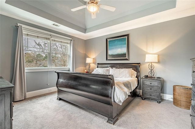 bedroom with ceiling fan, light carpet, and a tray ceiling