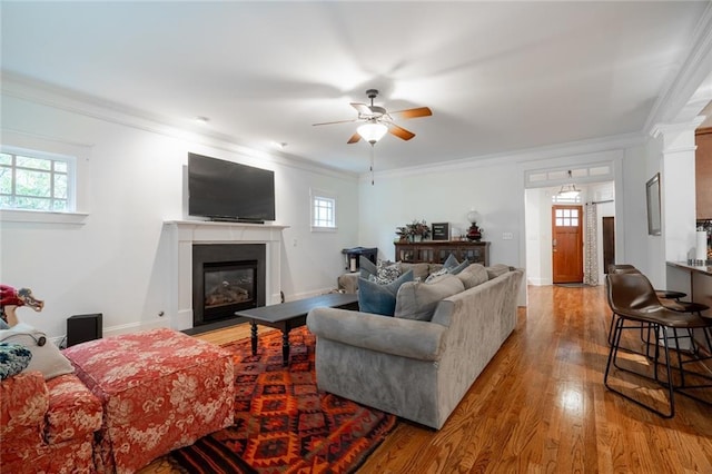 living room with ceiling fan, plenty of natural light, light hardwood / wood-style floors, and ornamental molding