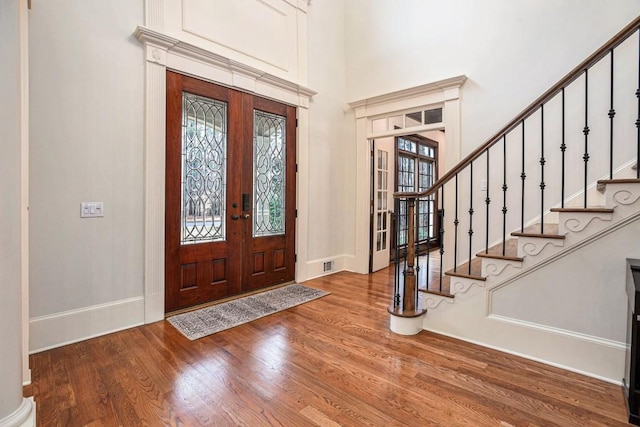 foyer with a towering ceiling, hardwood / wood-style floors, and french doors