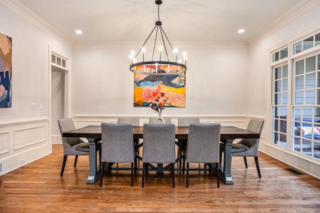 dining space with ornamental molding, hardwood / wood-style floors, and a notable chandelier