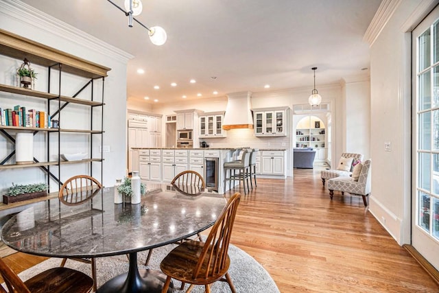 dining area with crown molding, a healthy amount of sunlight, light hardwood / wood-style floors, and wine cooler