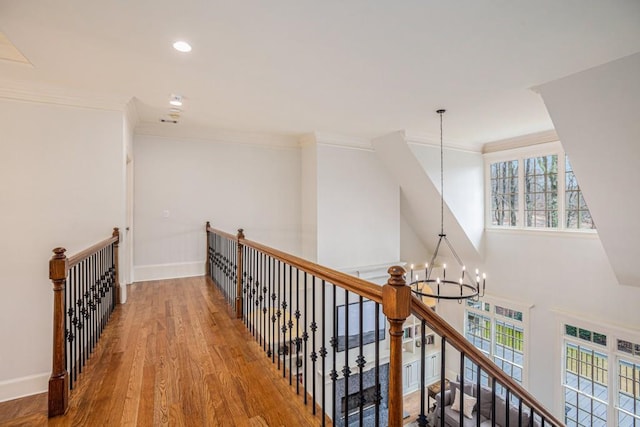 corridor with a towering ceiling, wood-type flooring, ornamental molding, and a chandelier