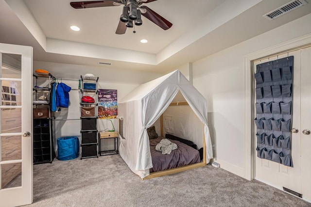 bedroom featuring a raised ceiling, carpet flooring, and ceiling fan