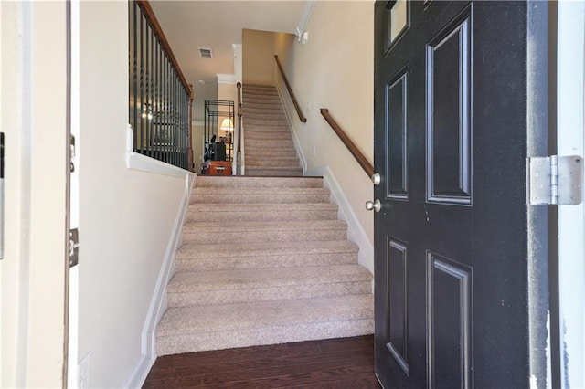 staircase featuring crown molding and wood-type flooring