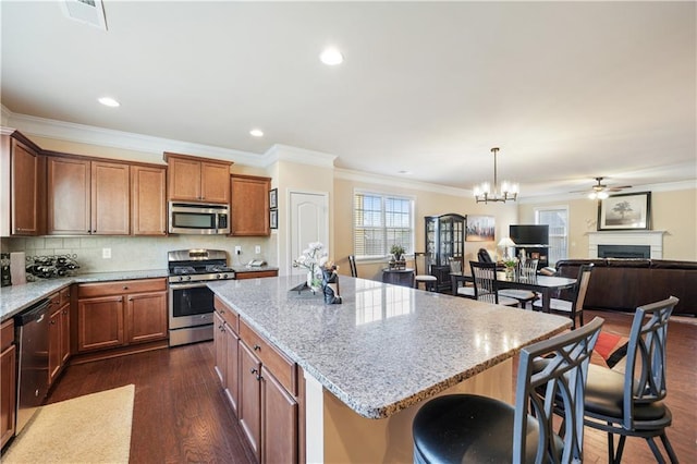 kitchen with a kitchen island, decorative backsplash, hanging light fixtures, stainless steel appliances, and light stone counters