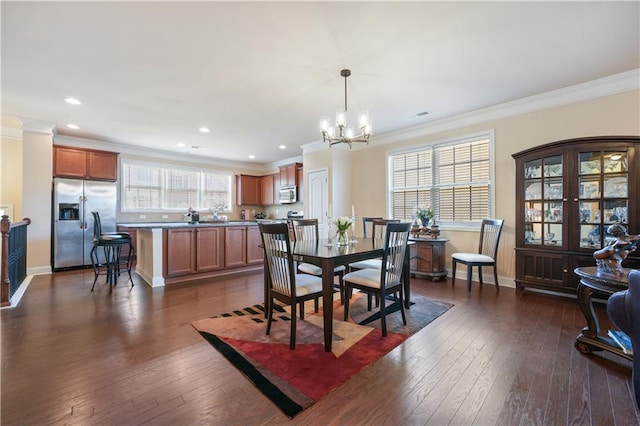 dining room featuring dark wood-type flooring, ornamental molding, and a notable chandelier