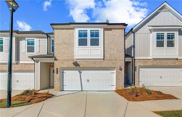 townhome / multi-family property featuring a garage, board and batten siding, concrete driveway, and brick siding