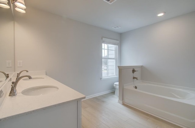 bathroom with toilet, an inviting chandelier, vanity, hardwood / wood-style flooring, and a washtub