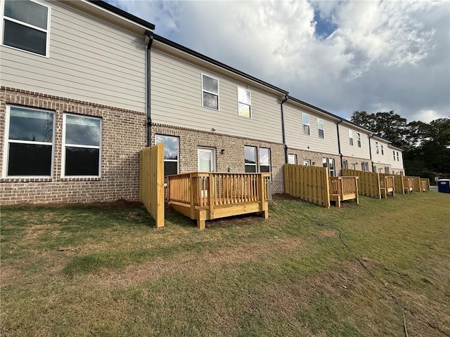 back of property featuring a wooden deck and a lawn