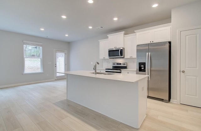 kitchen with white cabinetry, appliances with stainless steel finishes, sink, and a kitchen island with sink