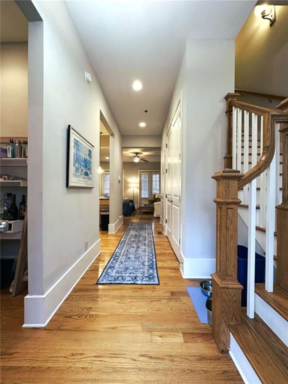 hallway with light wood finished floors, stairway, baseboards, and recessed lighting