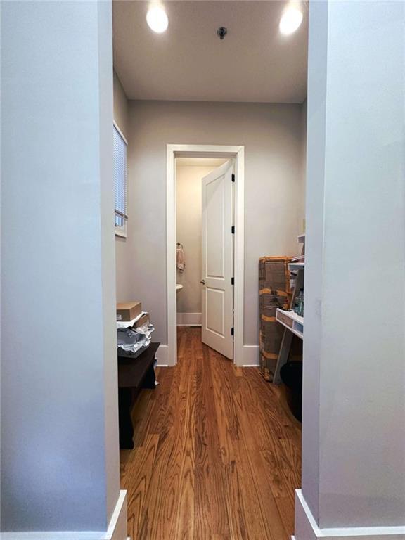 hall featuring baseboards, wood finished floors, and recessed lighting