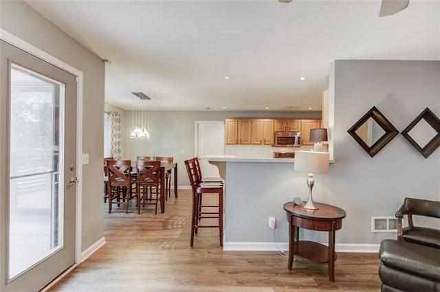 sitting room featuring light wood-type flooring, healthy amount of natural light, baseboards, recessed lighting, and a chandelier