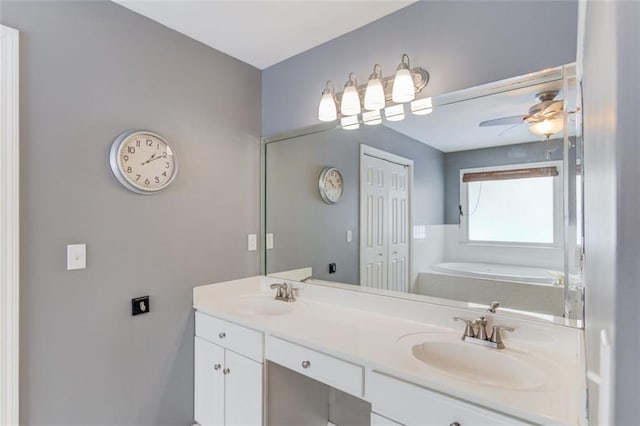 bathroom with double vanity, a bath, and a ceiling fan