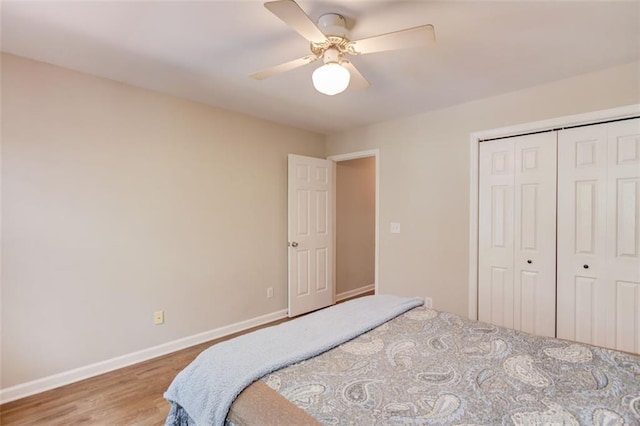 bedroom with baseboards, wood finished floors, a closet, and a ceiling fan