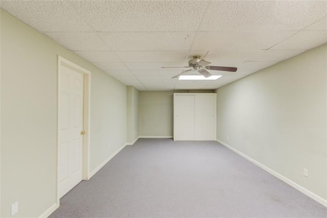 unfurnished bedroom with carpet floors, a ceiling fan, baseboards, and a drop ceiling