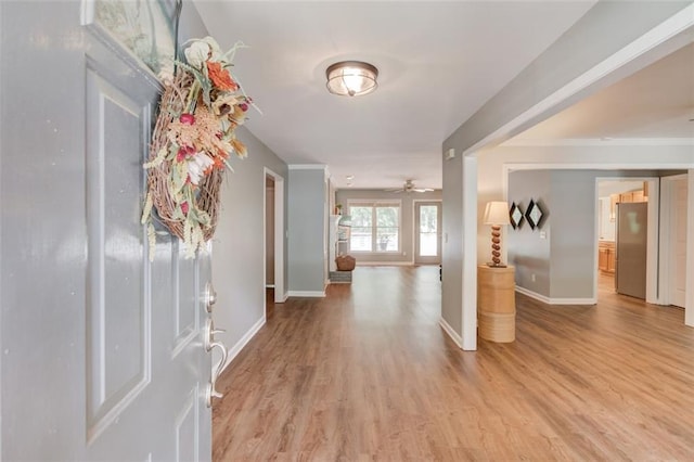 foyer with baseboards, light wood-style floors, and ceiling fan