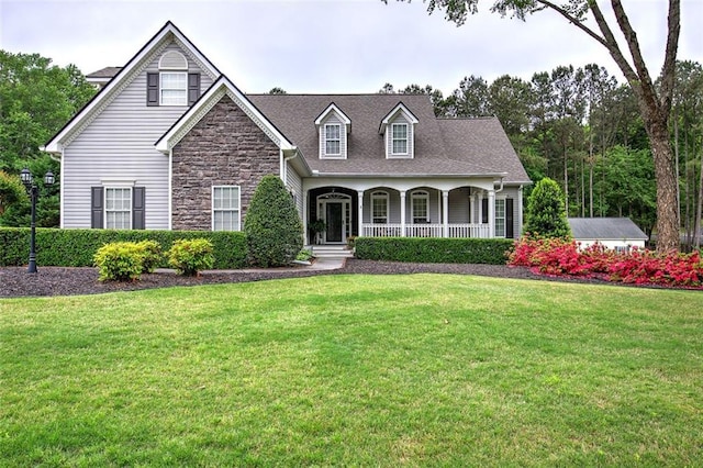 cape cod home with covered porch, stone siding, and a front lawn