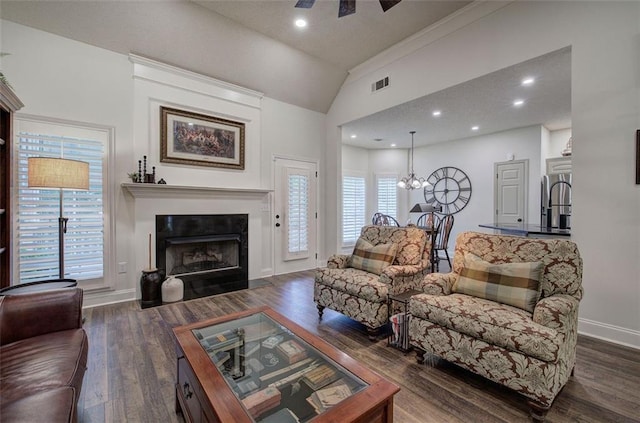 living area with visible vents, an inviting chandelier, wood finished floors, a fireplace with flush hearth, and vaulted ceiling