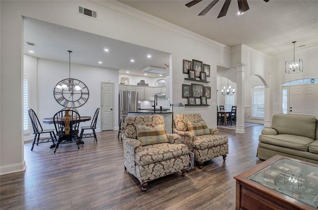 living area with visible vents, crown molding, dark wood-style flooring, a textured ceiling, and a chandelier