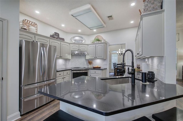 kitchen featuring a sink, dark countertops, stainless steel appliances, and a peninsula