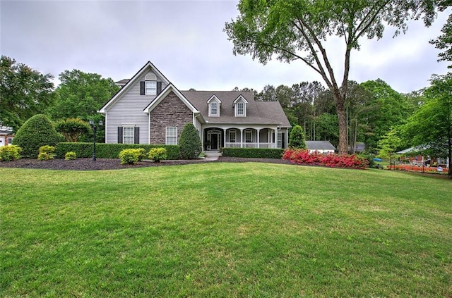 cape cod home with covered porch, a front yard, and stone siding