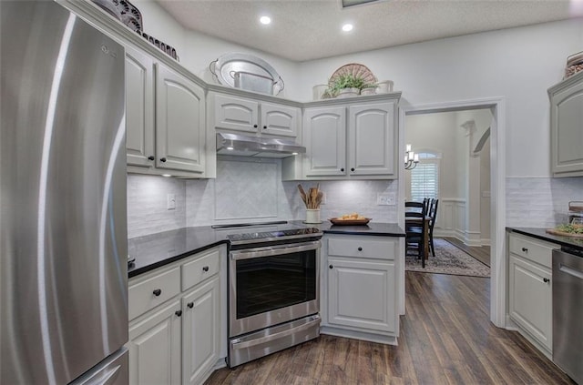 kitchen with dark countertops, tasteful backsplash, under cabinet range hood, stainless steel appliances, and recessed lighting