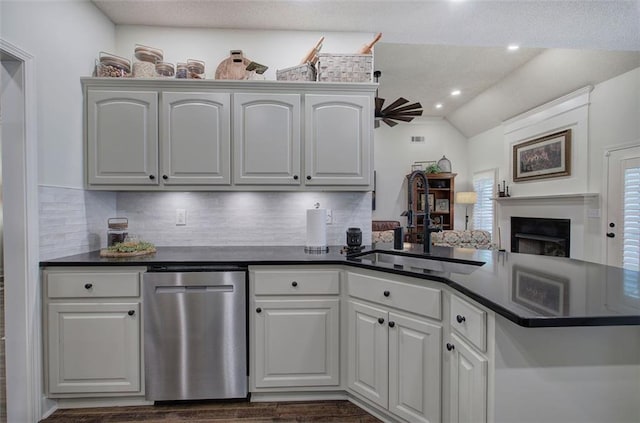 kitchen featuring dark countertops, decorative backsplash, a sink, and dishwasher