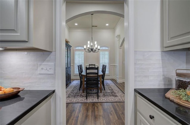 dining room with crown molding, arched walkways, dark wood-style floors, an inviting chandelier, and recessed lighting