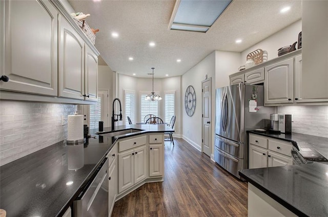 kitchen with dark countertops, appliances with stainless steel finishes, a sink, a peninsula, and recessed lighting