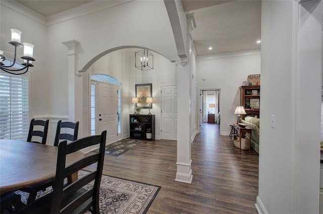 dining room featuring dark wood-style flooring, a high ceiling, a chandelier, baseboards, and ornamental molding