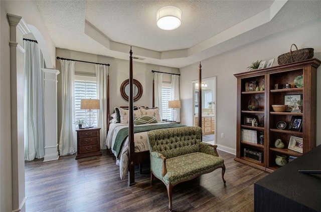 bedroom with a raised ceiling, dark wood finished floors, a textured ceiling, and visible vents