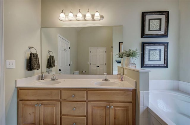 bathroom with double vanity, a sink, a garden tub, and toilet